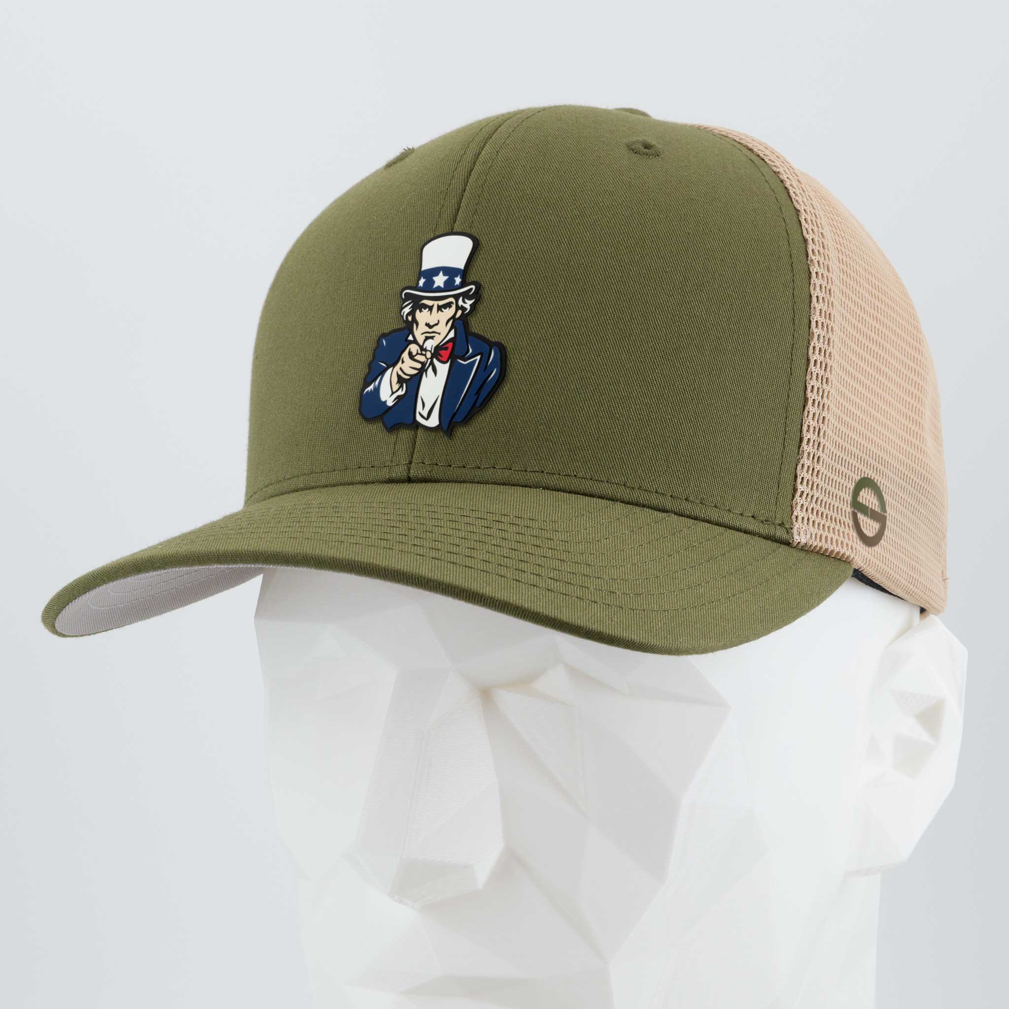 The Eternal Glyph Uncle Sam, I Want You! (Silicone) Flexfit® Mesh Trucker Cap in olive/khaki features a cartoon Uncle Sam pin and is displayed on a white mannequin head with a light gray background for classic American style.
