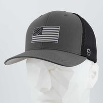 The Eternal Glyph American Flag, Monotone (Double Layer Silicone) Flexfit® Mesh Trucker Cap in Dark Gray/Black features a grayscale flag patch on the front, shown on a white geometric mannequin head against a plain background.