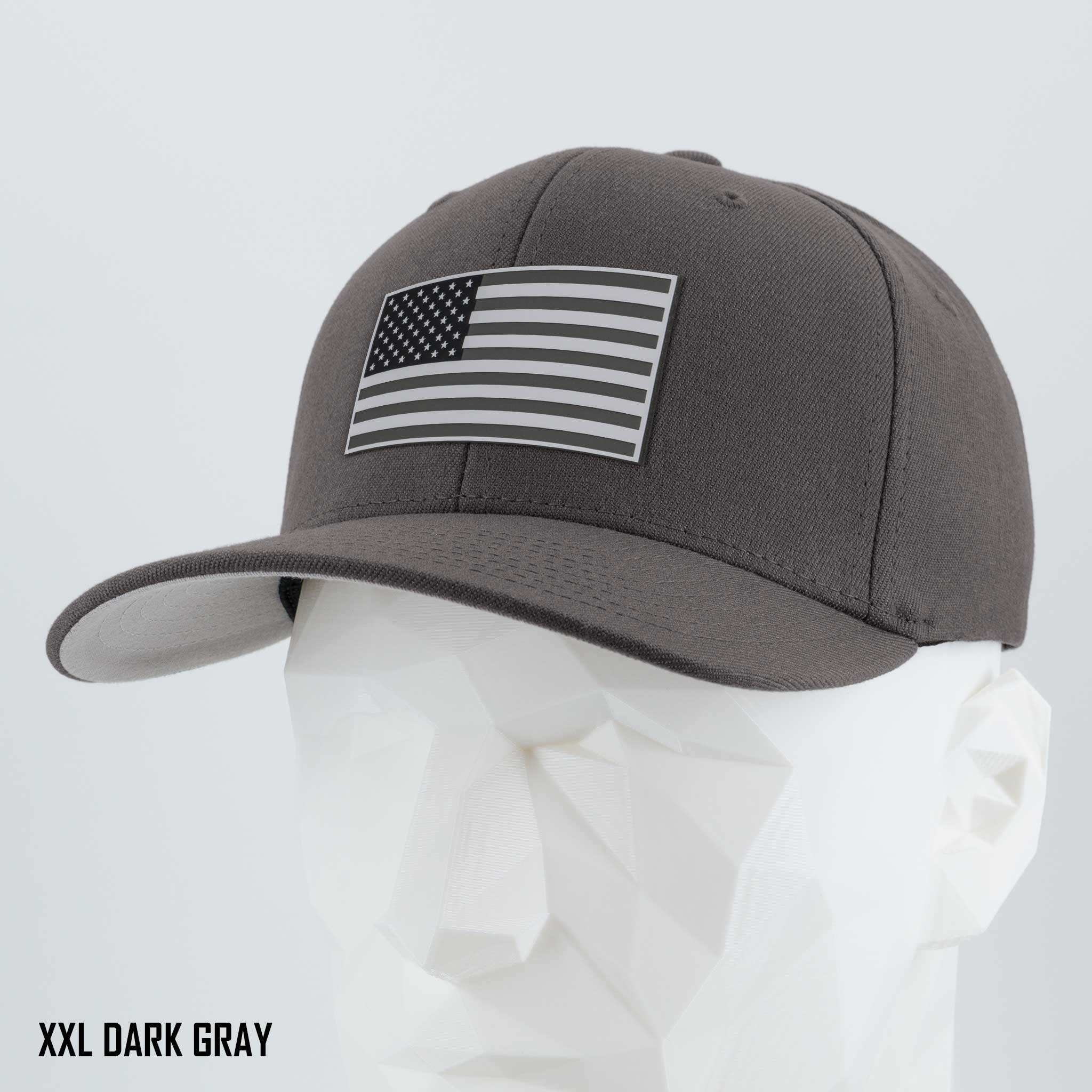 A dark gray Eternal Glyph Flexfit® Premium Wool Blend Cap featuring a monotone American flag silicone patch is displayed on a white geometric mannequin. The text "XXL DARK GRAY" appears in the bottom left corner.
