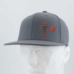 The Eternal Glyph Spiral Warrior Petroglyph (Silicone) Flexfit® Flat Bill Premium Fitted Cap features an orange Moab-inspired design on gray, shown on a white mannequin head.